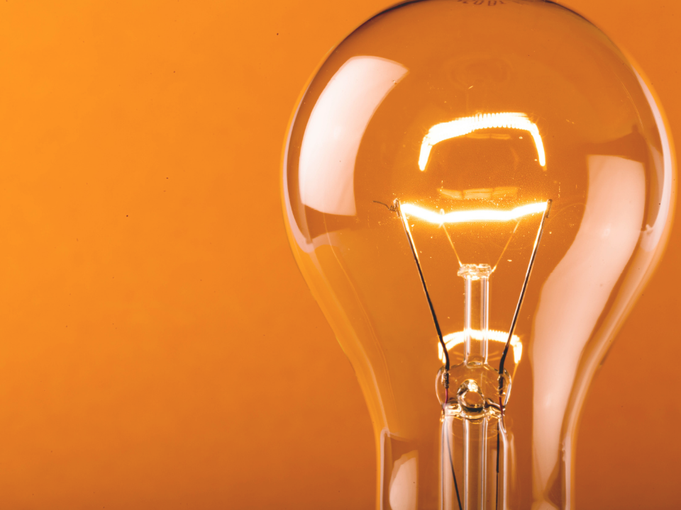 Lightbulb lit up in front of an orange background