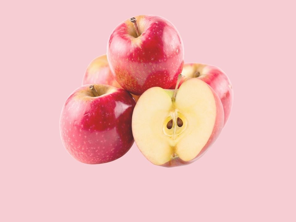 Five pink lady apples in front of a light pink background.
