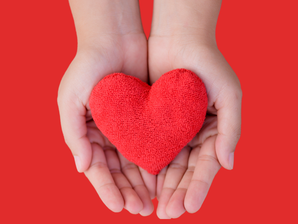 red background with hands holding a fabric heart in it