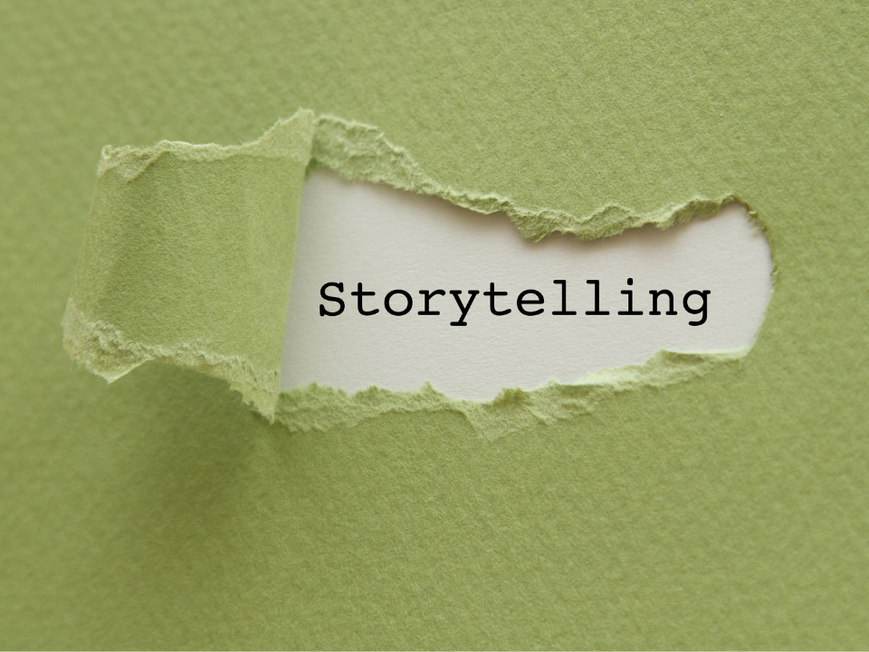 Piece of green paper ripped to reveal the word "storytelling" underneath it