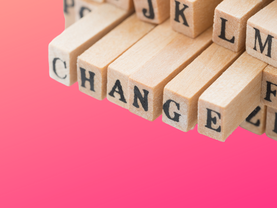 wooden blocks on a pink background that spell out the word "change."