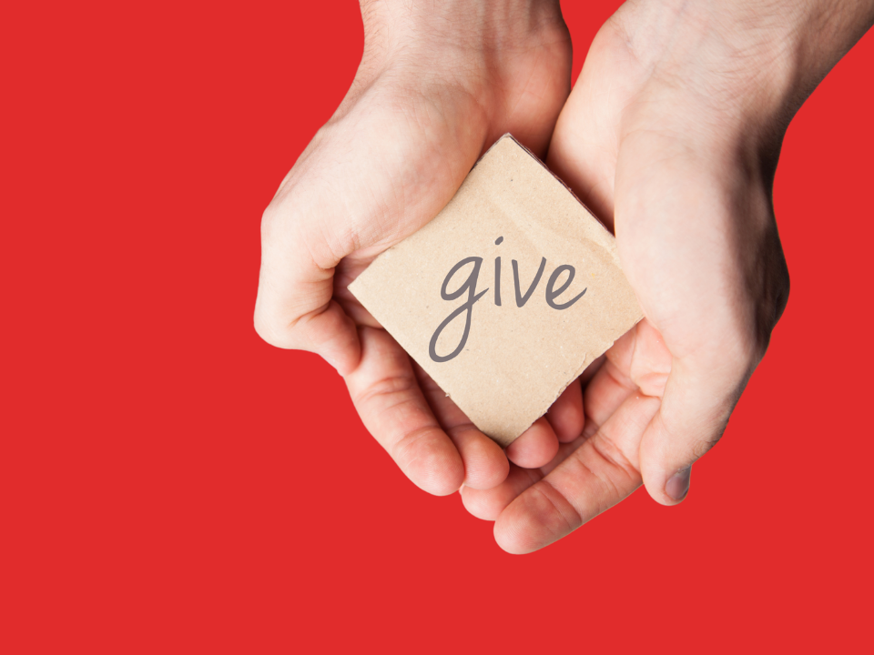 Hand holding a block with the word "give" on it, over a red background