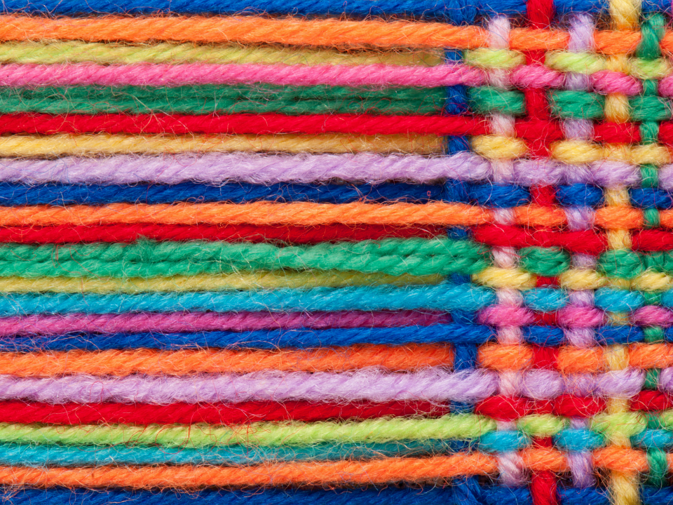 Bright multi-colored strings of yarn weaving together