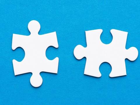 Two white puzzle pieces in front of a blue background