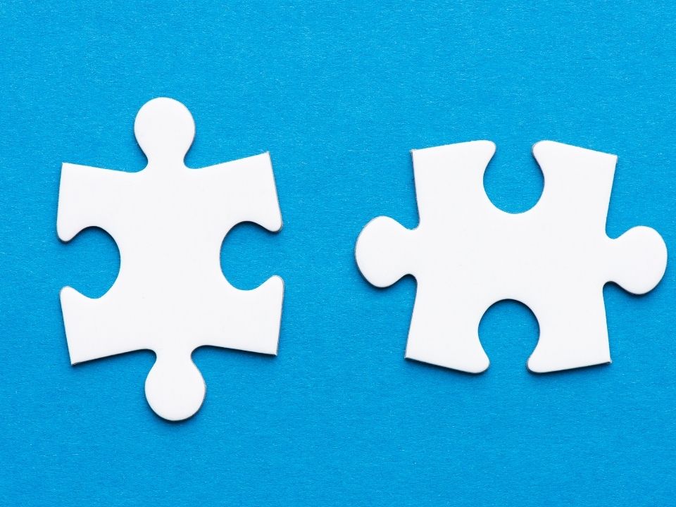 Two white puzzle pieces in front of a blue background