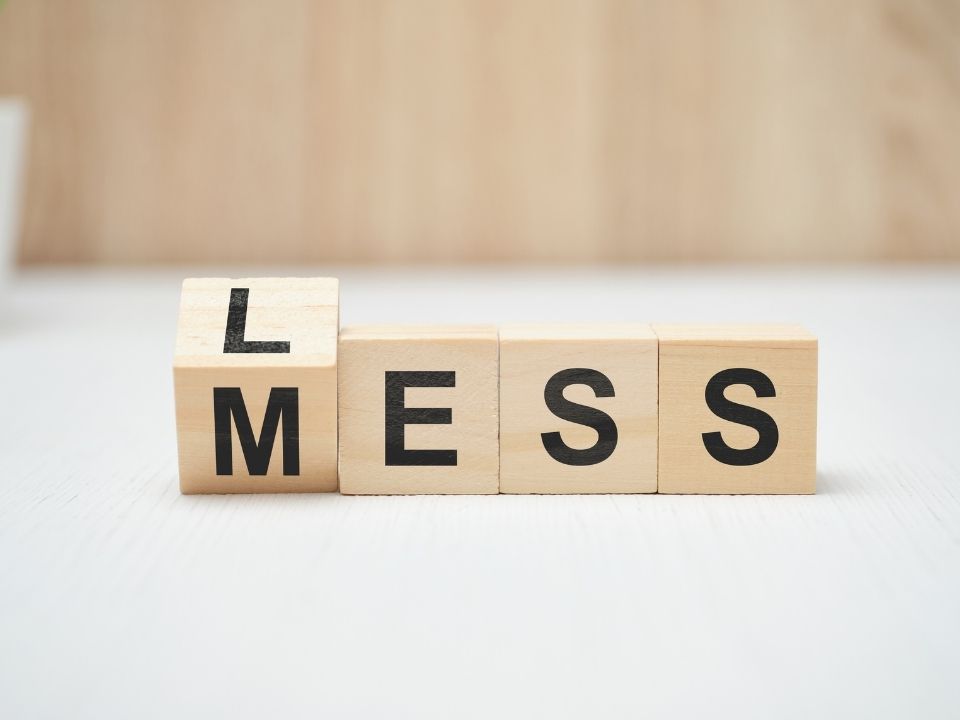 Wooden blocks spelling out the words "less" and "mess."