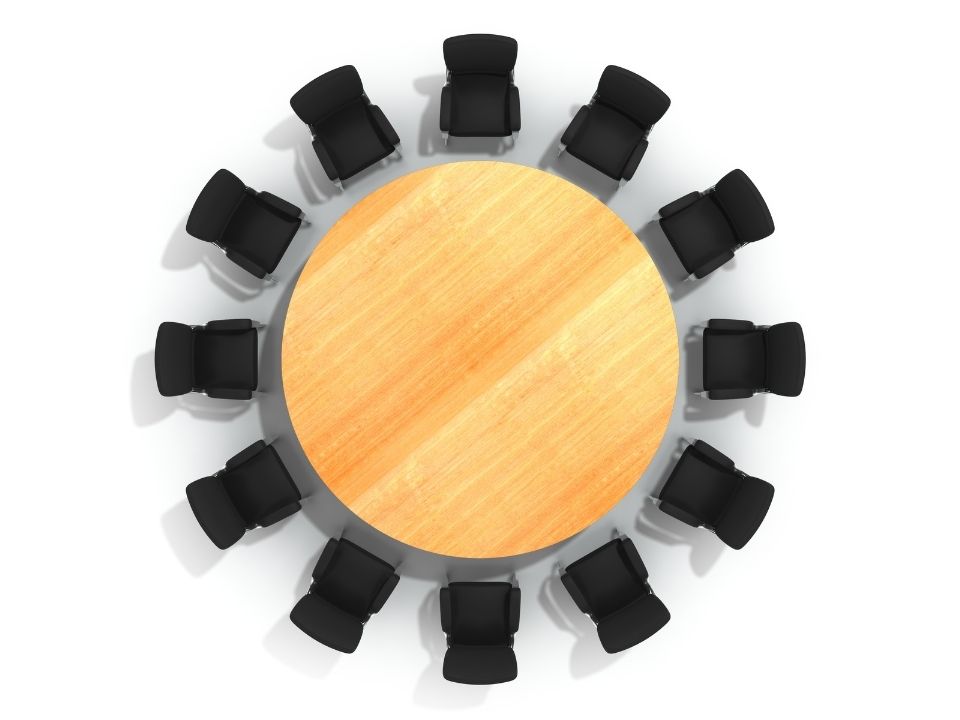 Round table with black chairs placed around it in a circle.