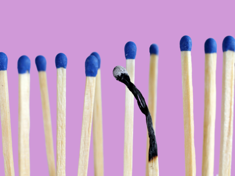 Matches with blue tips in front of a lilac background. One of the matches is completely burned all the way down.