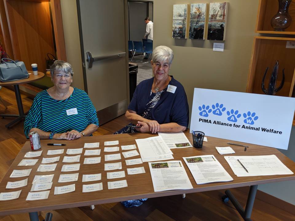 Two PAAW volunteers sitting at the registration table with nametags and a PAAW sign
