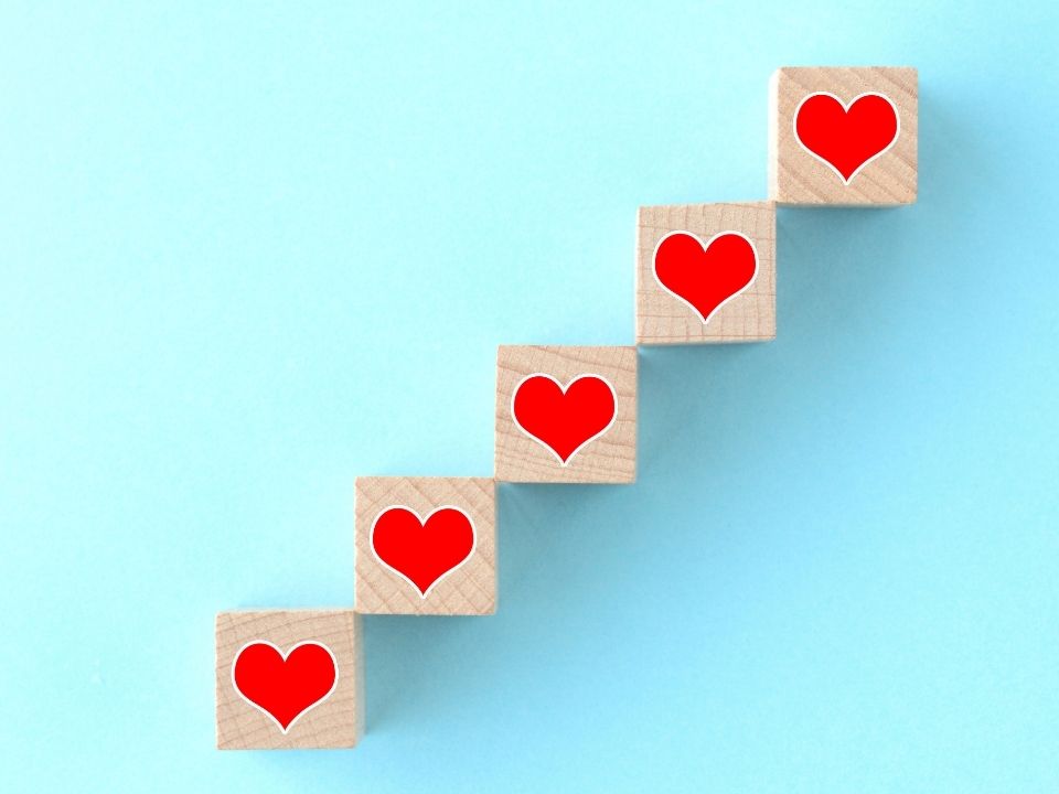 Wooden blocks with red hearts stacked in an upward motion from bottom left to top right.