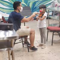 Adult showing child how to play a violin.