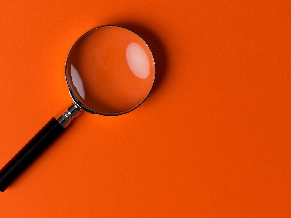 Magnifying glass in front of an orange background.