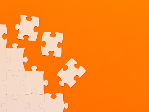 Puzzle pieces in front of an orange background
