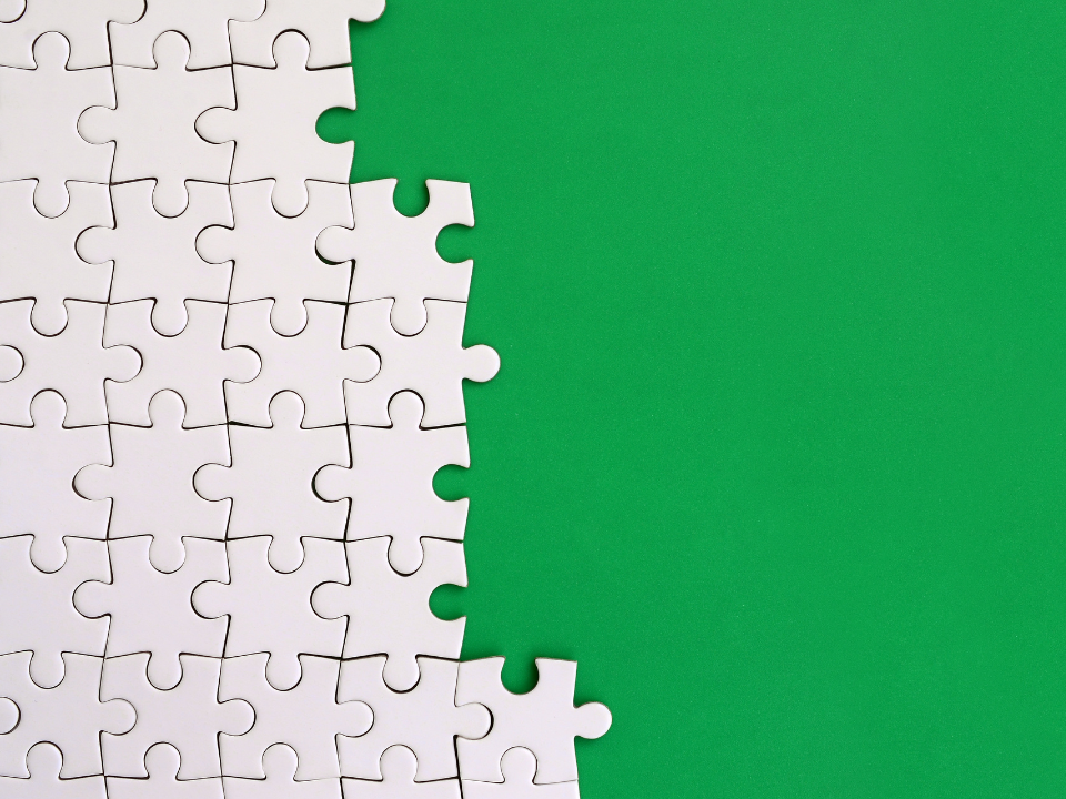 Puzzle pieces that are white and half way done with a green background.