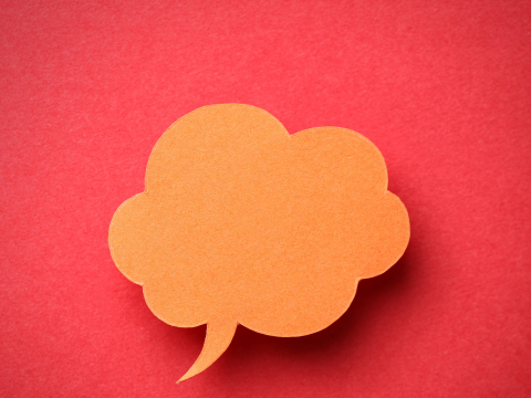 Orange sticky note in the shape of a thought bubble in front of a red background
