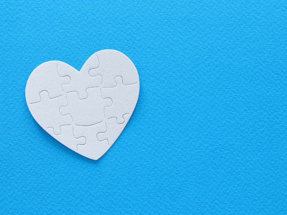 A white heart that's a puzzle with a blue background.