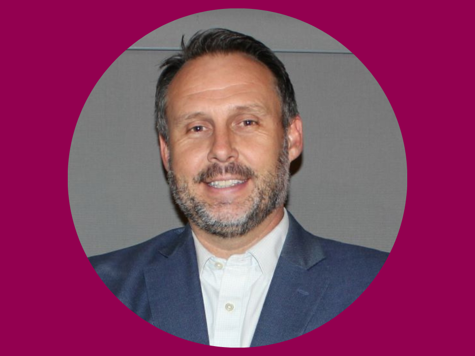 A guy smiling at a picture with a purple background.