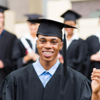 Photo of Black man in black graduation cap and gown holding a diploma