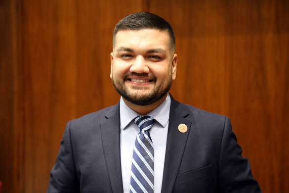 Photo of Andres Cano in a suit in front of a brown wood panel wall