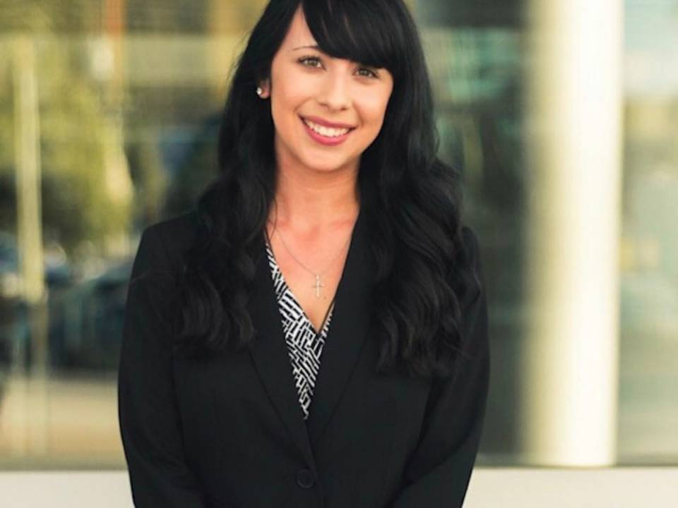 Young woman with dark hair is smiling while wearing professional clothing