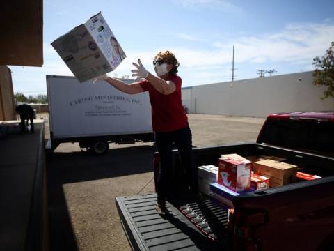 Woman in protective mask catches box while standing in the back of a pickup truck