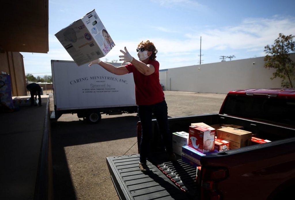 Woman in protective mask catches box while standing in the back of a pickup truck