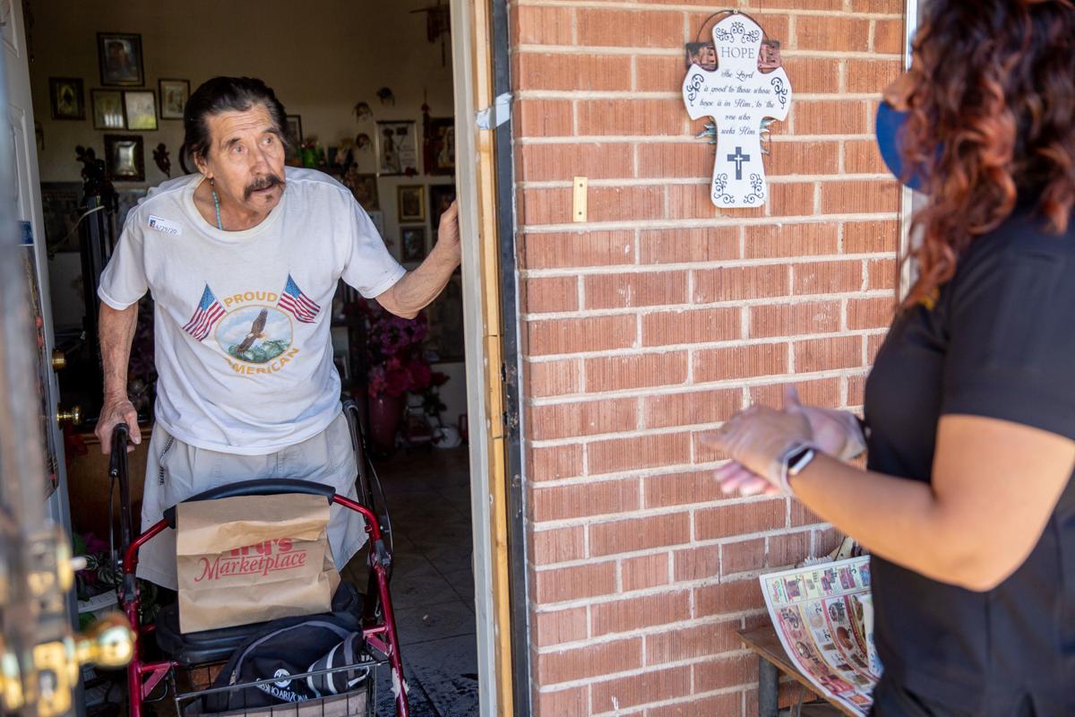 Elderly man answers door with a walker.