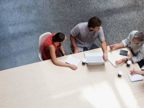 Group of professionals gathered around a table with notebooks and a laptop.