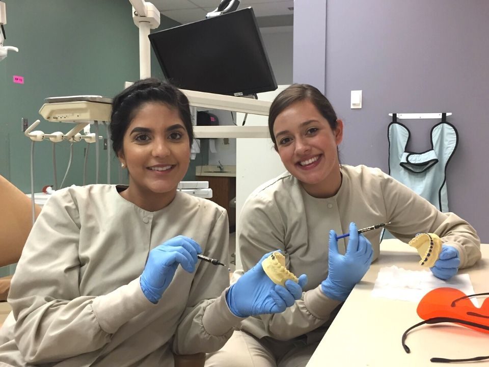 Two young women in a dental setting smiling