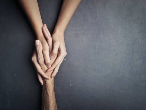 Pair of holding hands on a gray background