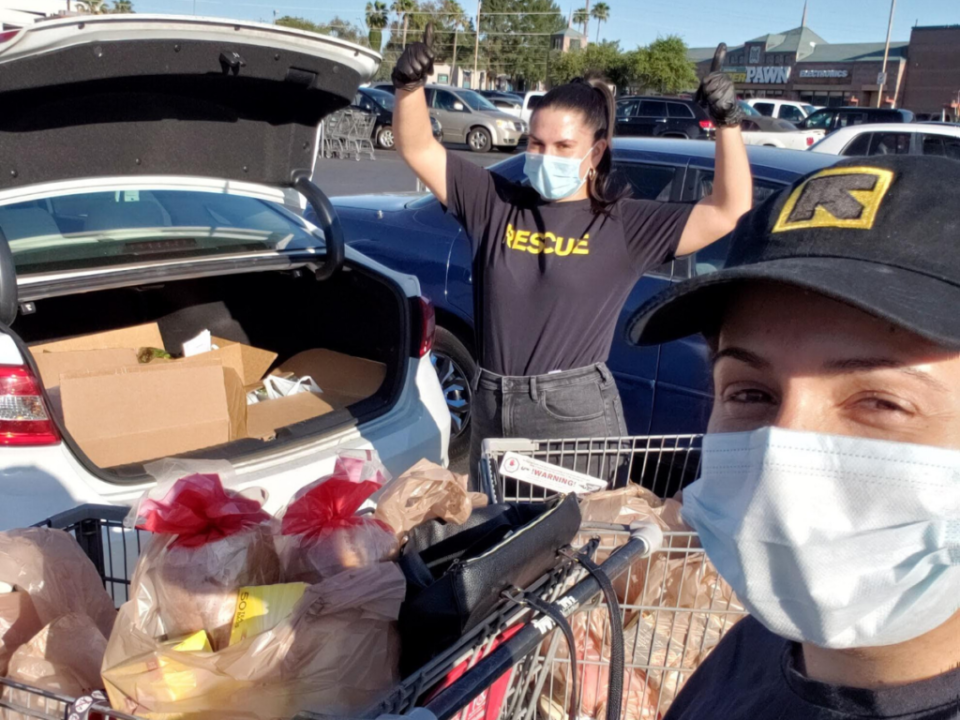Twp individuals with masks load groceries into the trunk of a car